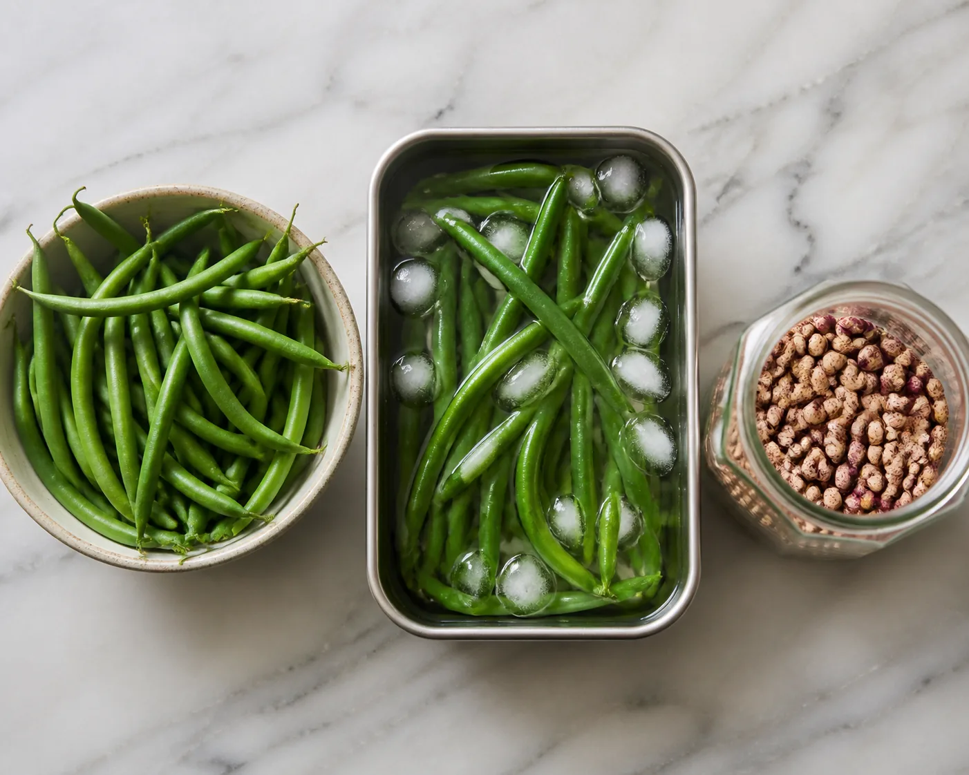 Three forms of the same crop side by side on a counter, a bowl of fresh green snap beans, a tray of blanched beans cooling in ice water, and an open jar of hard dry speckled beans