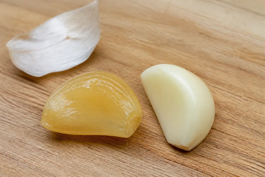 Translucent amber waxy garlic clove beside a firm opaque cream clove