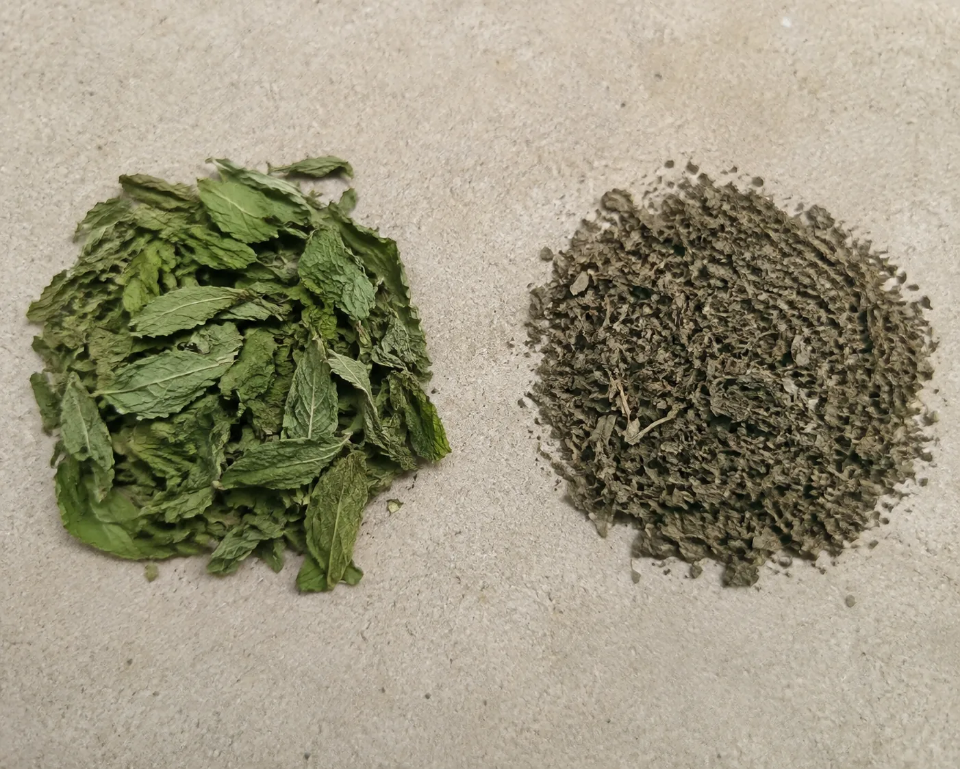 Whole green dried leaves beside a pile of darker, finely crumbled dried leaves